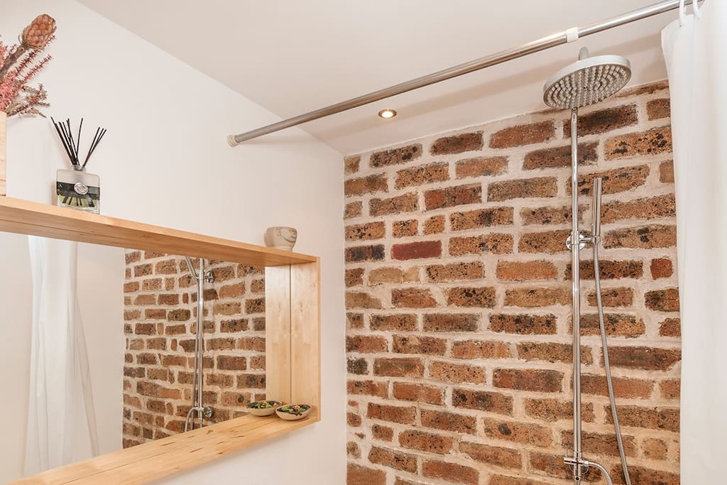 Contemporary bathroom with rain shower over bath, feature stone wall and underfloor heating