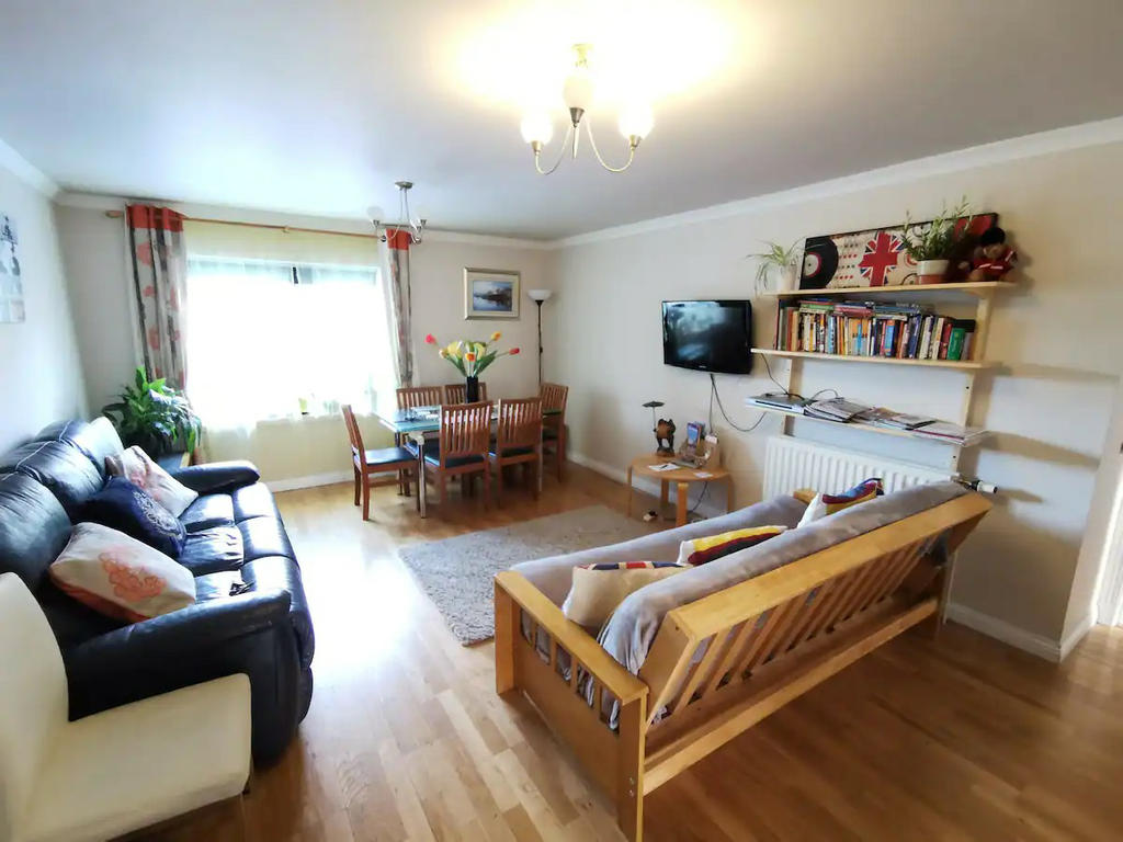 Large living room with 2 sofas and a dining table, open view towards Meadowbank church