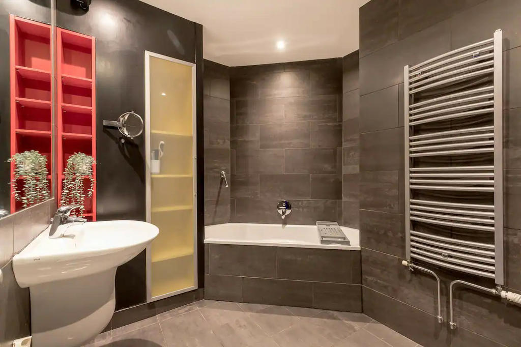 Spacious bathroom, with corner bath and separate shower in marble tiles